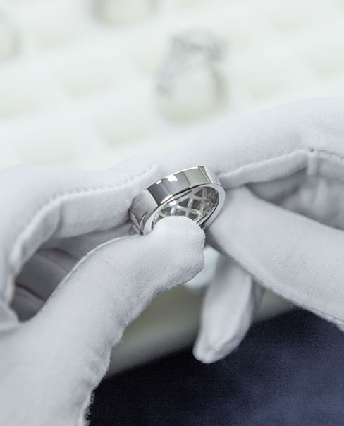 gloved hands holding a thick silver ring
