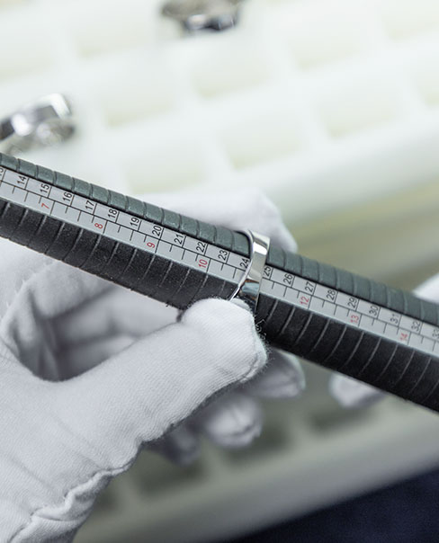 gloved hand measuring the inner diameter of a silver ring