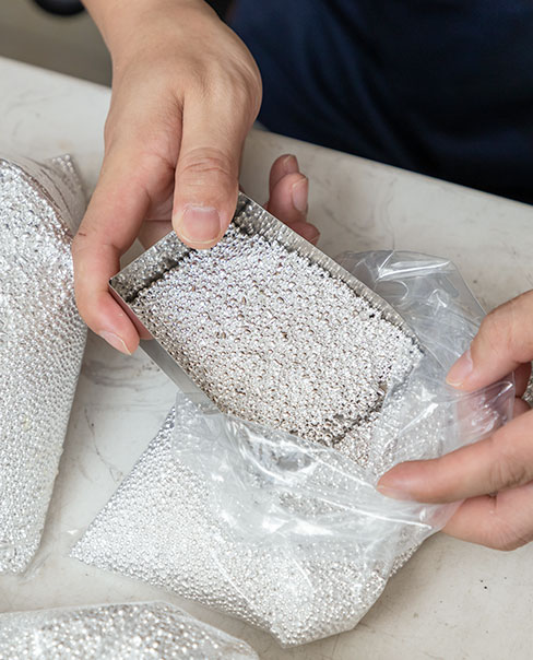 hand holding a box filled with small while beads